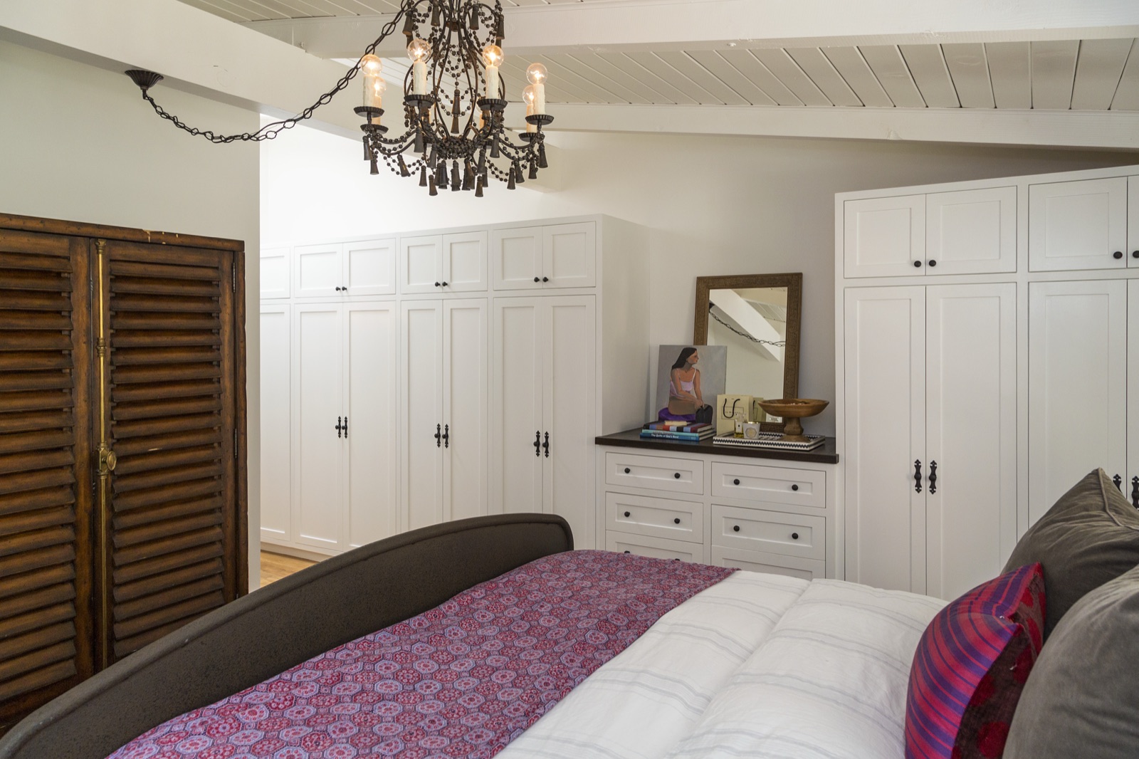 Master suite at 855 Jacon Way Pacific Palisades, full floor-to-ceiling custom white shaker wardrobe millwork with banded center drawers, antique louvred dressing-room doors, oil-rubbed hardware. Custom built-ins by ESRL Development.